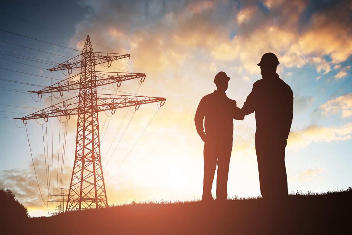 Shaking hands next to electrical pylon
