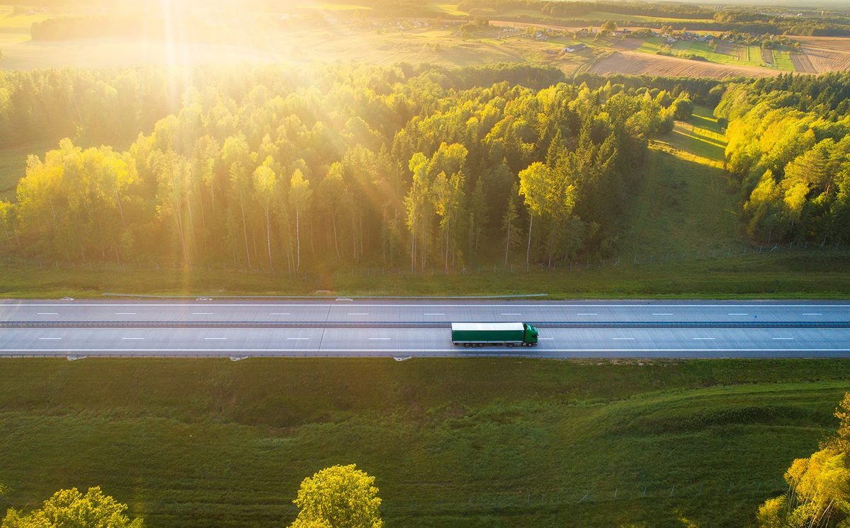 green-truck-morning-timedriving-on-highway-surrounded-by-forrest-smaller