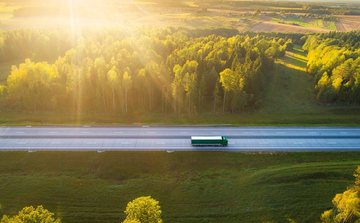 green-truck-morning-timedriving-on-highway-surrounded-by-forrest-smaller